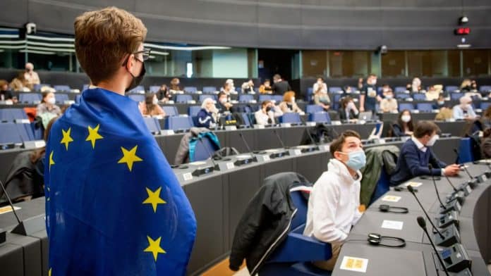 A guy with the Union Europe's flag standing at the European Youth Parlament